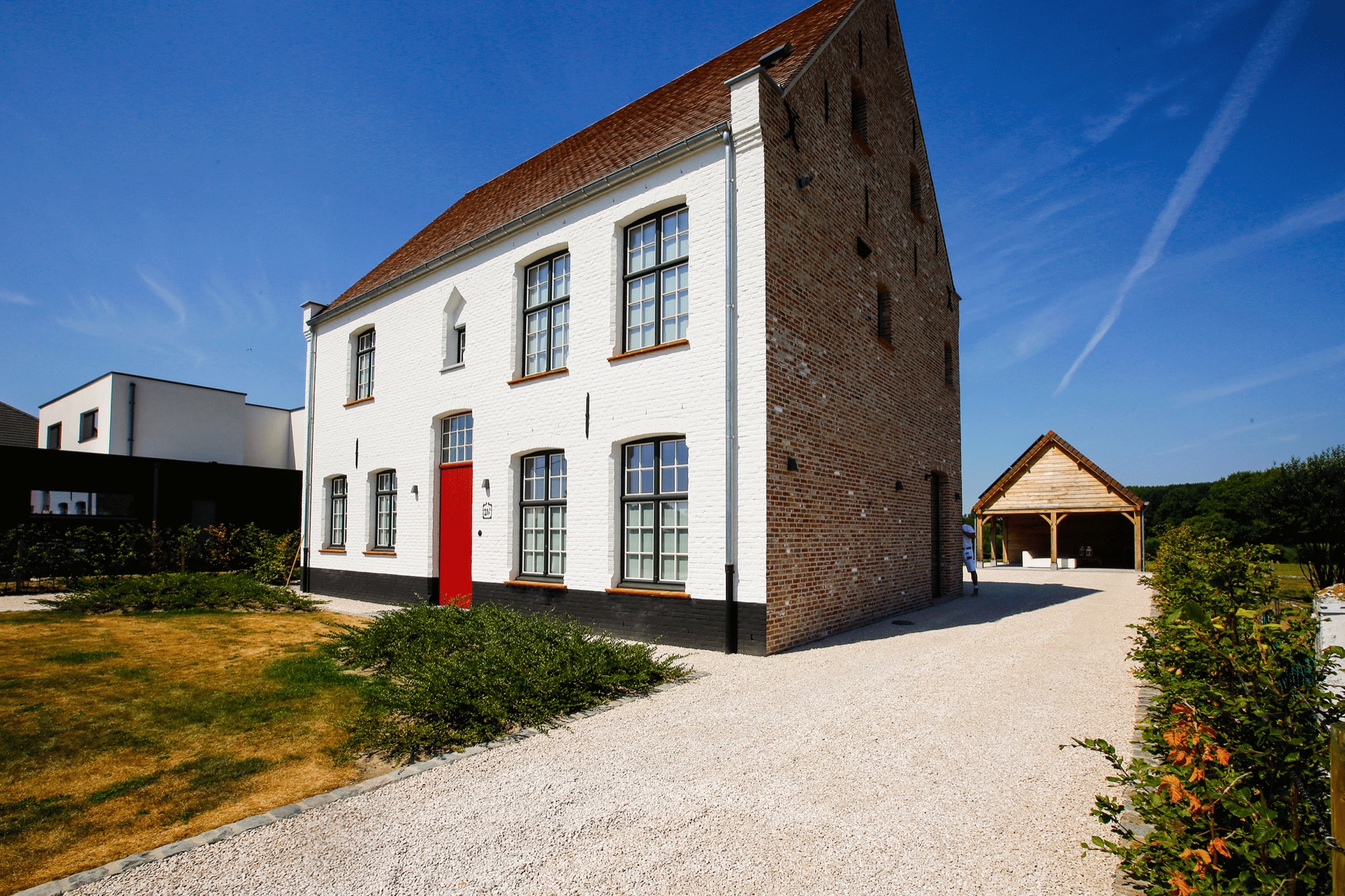 Gerenoveerde witte gevel met rode voordeur door Buyck